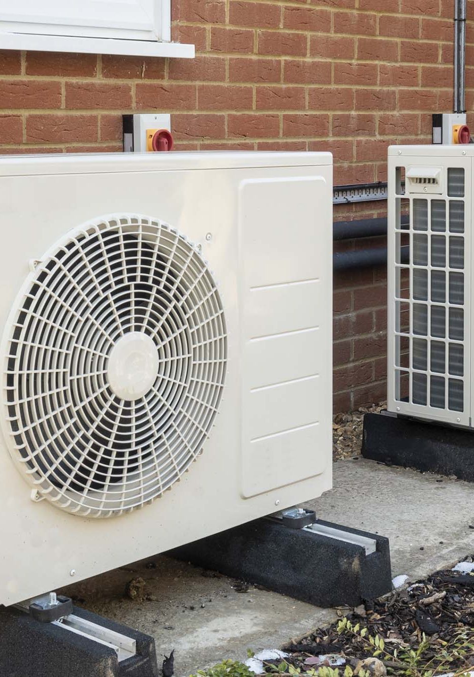 Two air source heat pumps installed on the exterior of a modern house